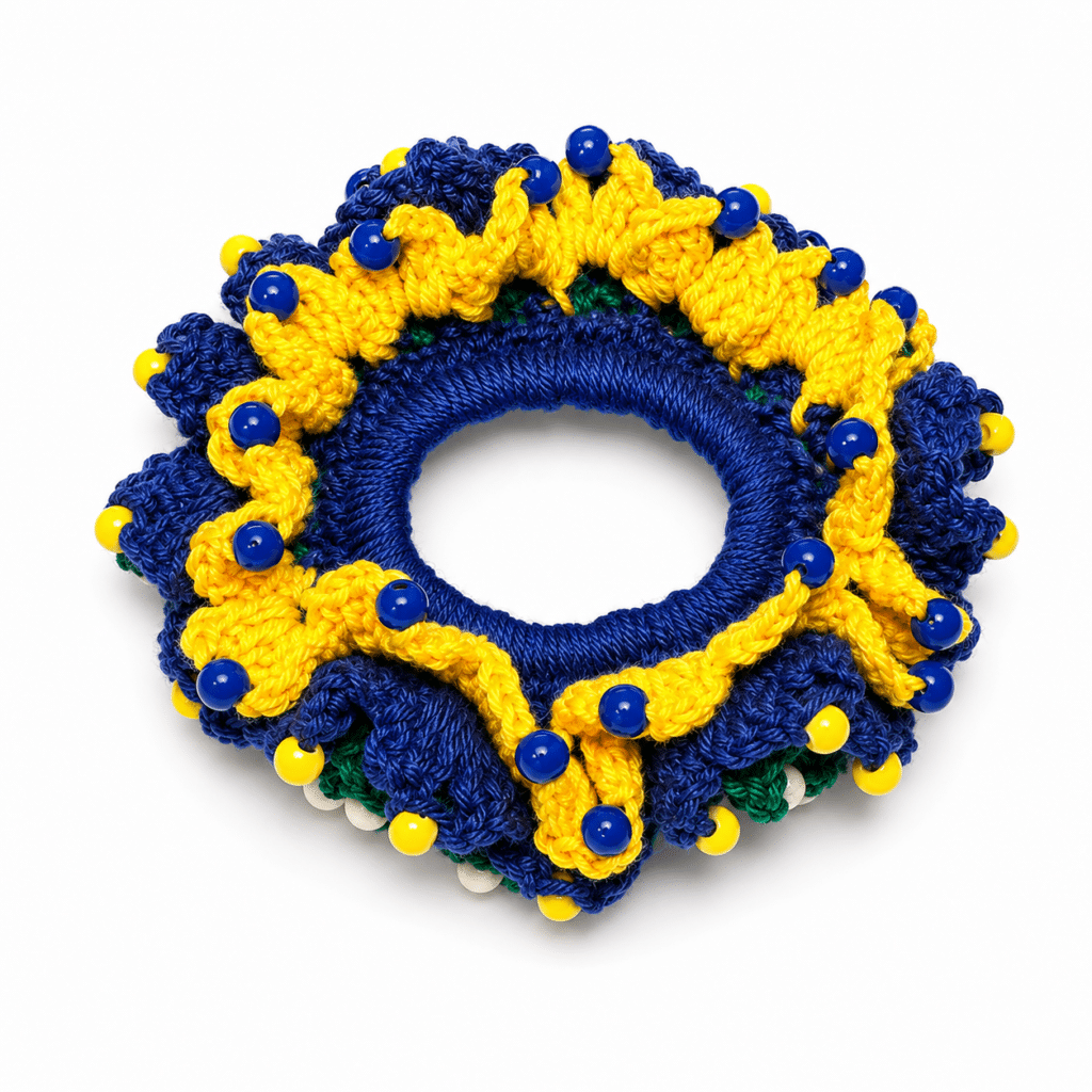 Xuxinha scrunchie de crochê nas cores do Brasil (azul, verde e amarelo) com aplicação de minipérolas, fundo branco.