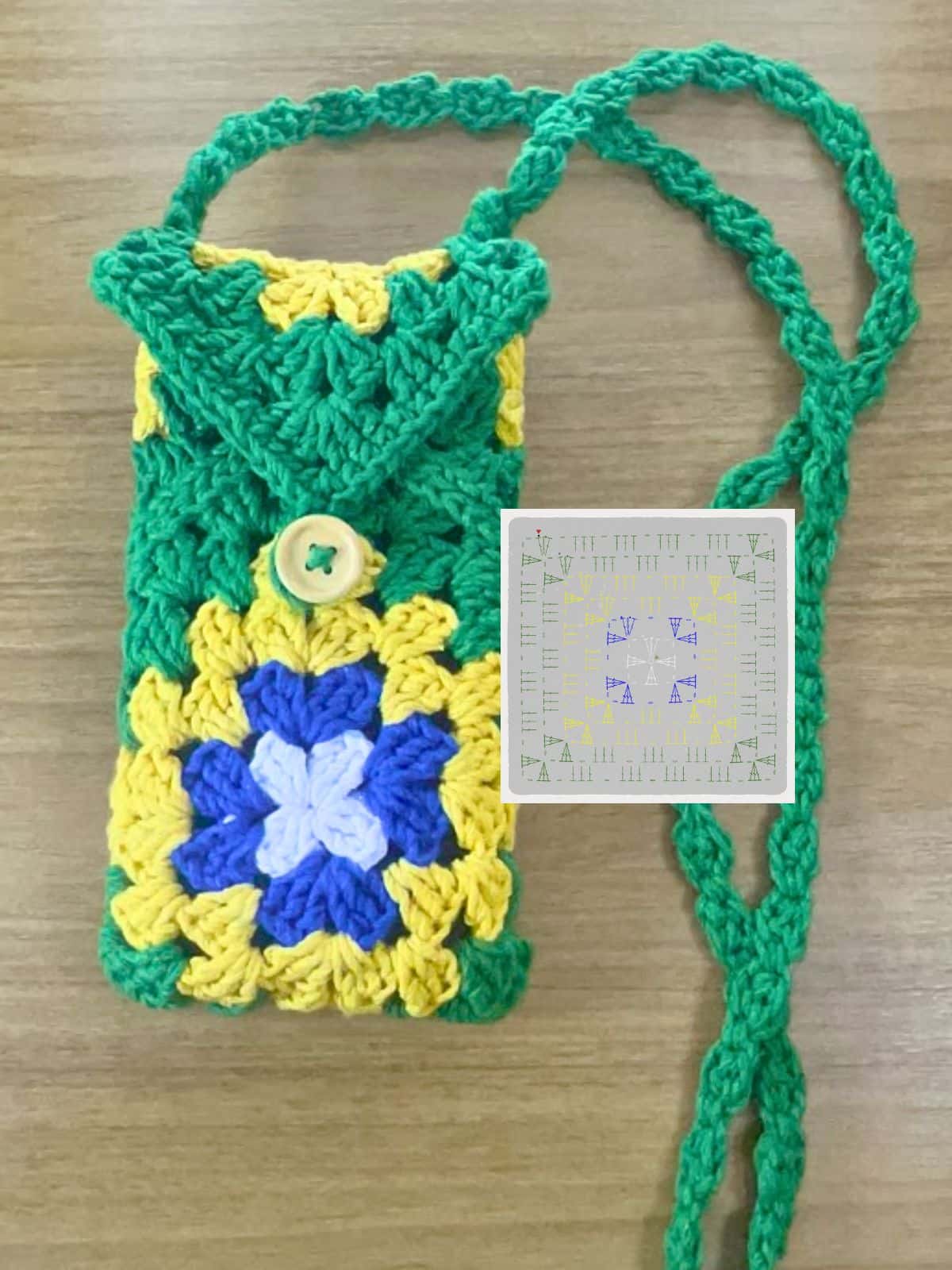 Bolsa Porta Celular de crochê transversal (crossbody) feita com granny squares coloridos, alça longa e fechamento seguro com botão.