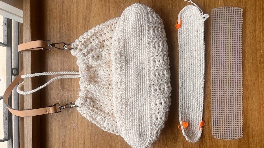 Bolsa de crochê simples e elegante modelo Lara montada com alça de couro e esquema dos elementos de estruturação do fundo oval.
