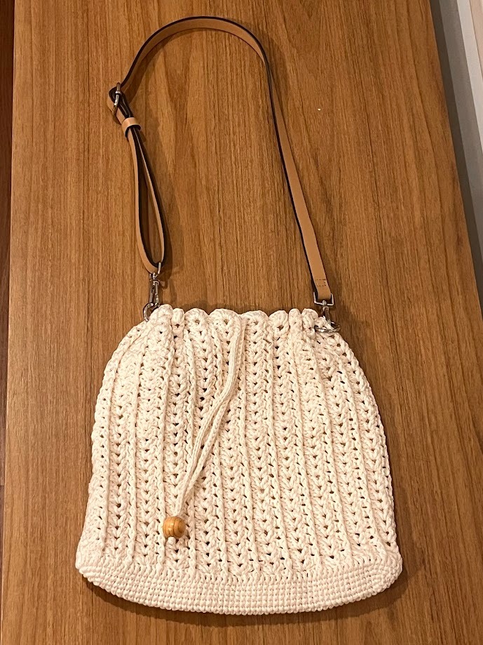 Bolsa de crochê simples e elegante modelo Lara finalizada com alça de couro e cordão de amarração com acabamento em conta de madeira artesanal